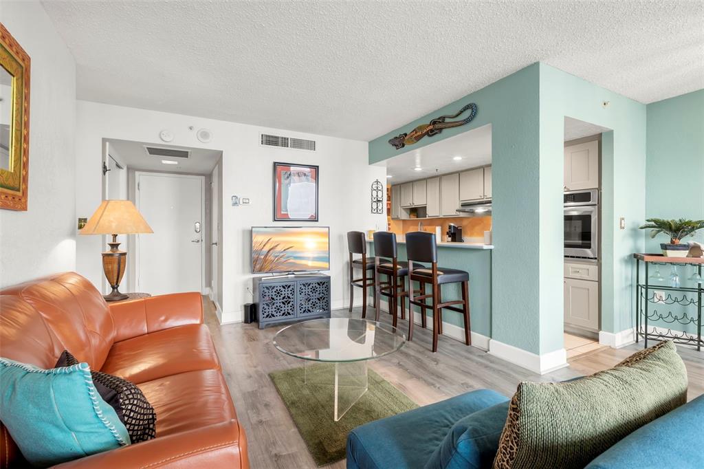 A living room with a leather sofa, glass coffee table, and an open kitchen bar — 470 3RD STREET S UNIT 613, ST PETERSBURG, FL