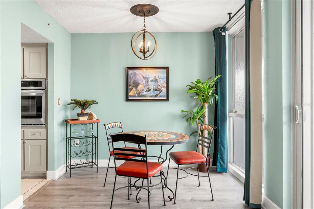 A dining area with a mosaic table, red chairs, light green walls, and a pendant light — 470 3RD STREET S UNIT 613, ST PETERSBURG, FL