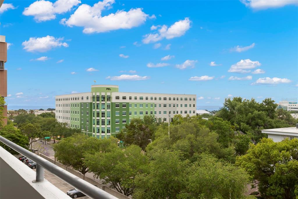 An elevated view from a balcony overlooking a green building, trees, and a blue sky — 470 3RD STREET S UNIT 613, ST PETERSBURG, FL