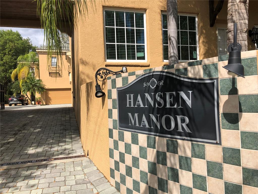 A sign reading Hansen Manor is mounted on a tiled wall beside a paved driveway — 2902 HANSEN MANOR LANE, TAMPA, FL