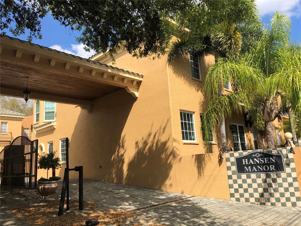 A tan stucco building with a covered entryway and a checkered sign reading Hansen Manor — 2902 HANSEN MANOR LANE, TAMPA, FL