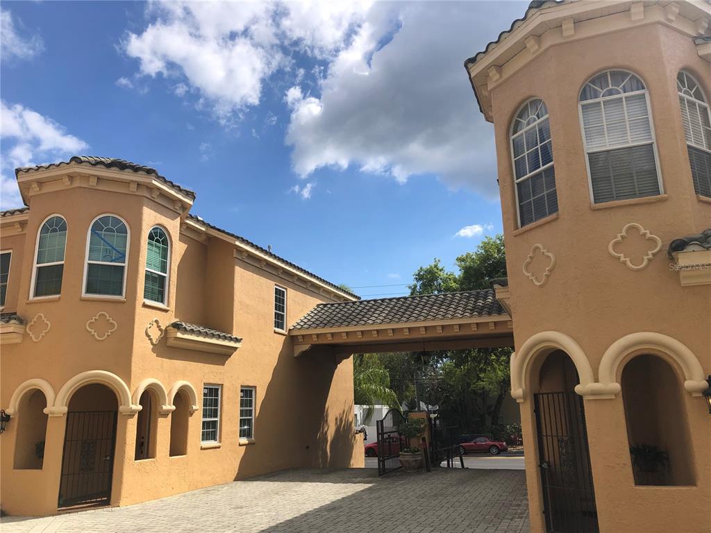 A tan stucco building with arched windows and a covered driveway under a blue sky — 2902 HANSEN MANOR LANE, TAMPA, FL