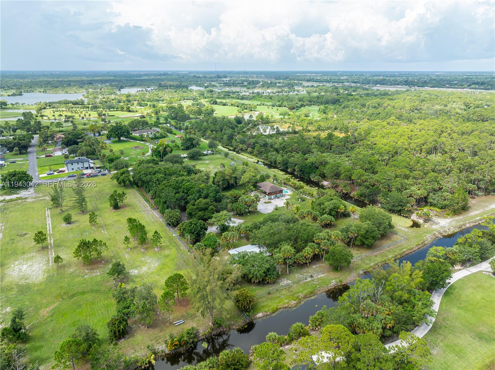 An aerial view shows a house surrounded by trees, a canal, and open green space — 576 Marshall Rd, West Palm Beach FL 33413, WEST PALM BEACH, FL