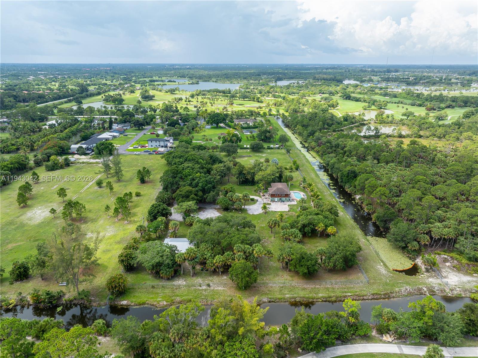 An aerial view shows a house with a pool surrounded by trees and canals — 576 Marshall Rd, West Palm Beach FL 33413, WEST PALM BEACH, FL