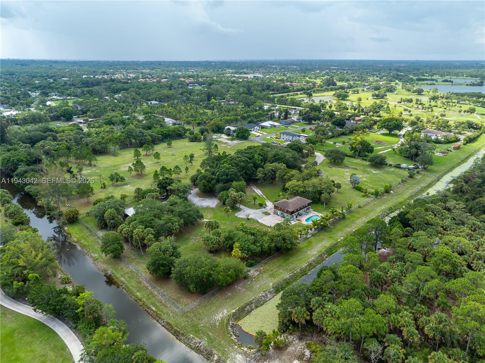 An aerial view shows a house with a pool situated on a large, wooded lot — 576 Marshall Rd, West Palm Beach FL 33413, WEST PALM BEACH, FL