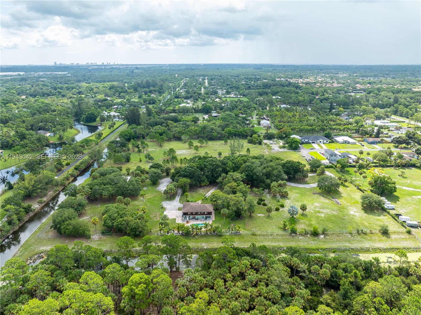 An aerial view shows a house with a pool surrounded by trees and grassy fields — 576 Marshall Rd, West Palm Beach FL 33413, WEST PALM BEACH, FL