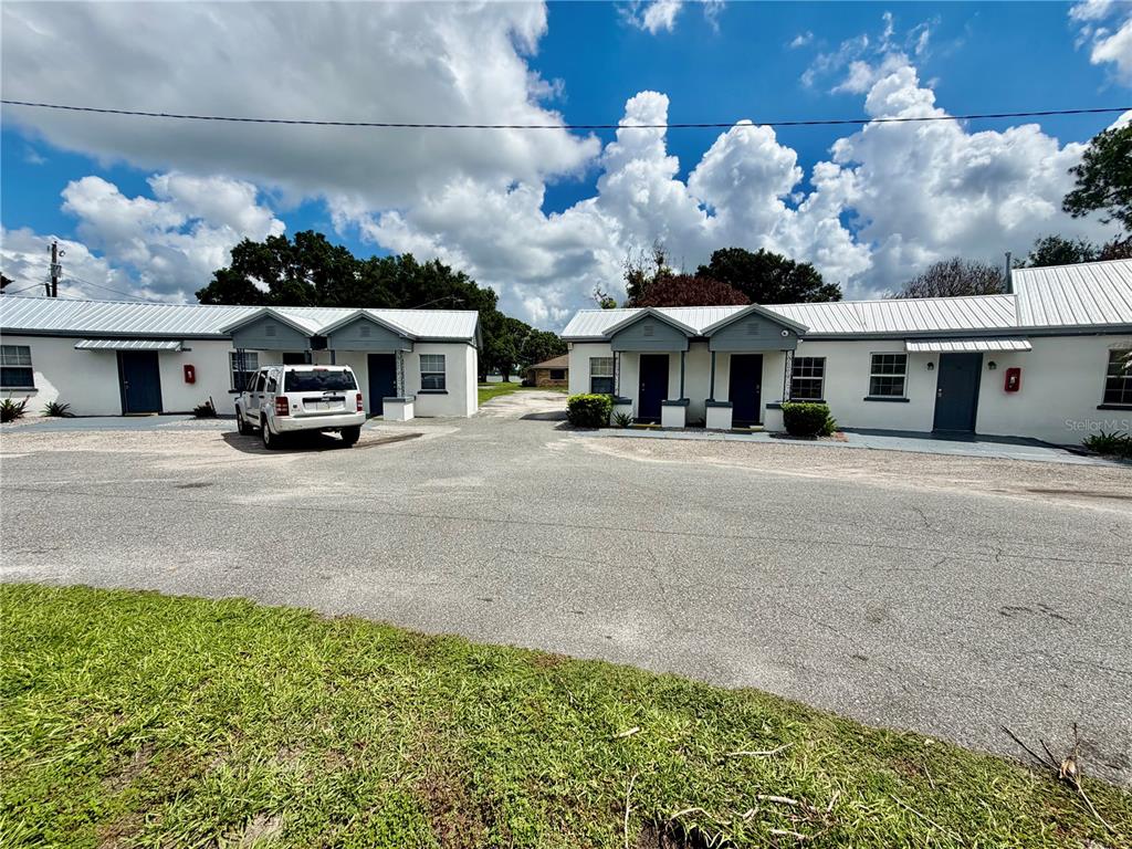 A single-story multi-unit building with a gravel parking area and a white SUV parked outside — 1702 1/2 US HIGHWAY 92 W, AUBURNDALE, FL