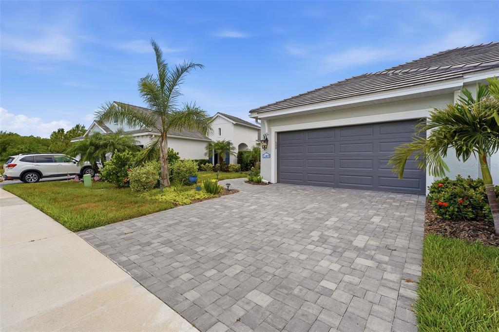 A paved driveway leads to a two-car garage of a single-story house with palm trees — 12468 PALATKA DRIVE, VENICE, FL