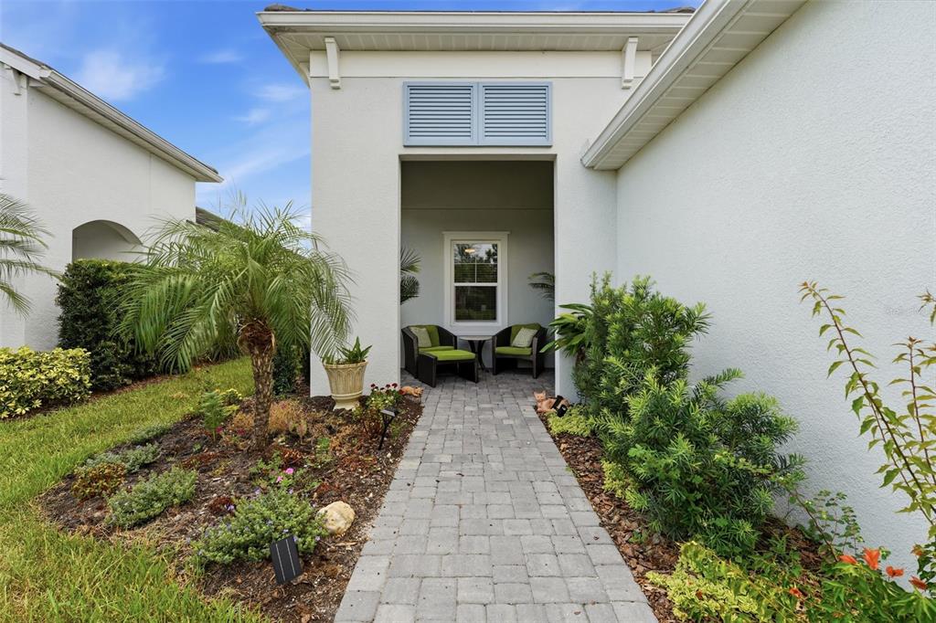 A paved walkway leads to a recessed entryway with two chairs and a window — 12468 PALATKA DRIVE, VENICE, FL