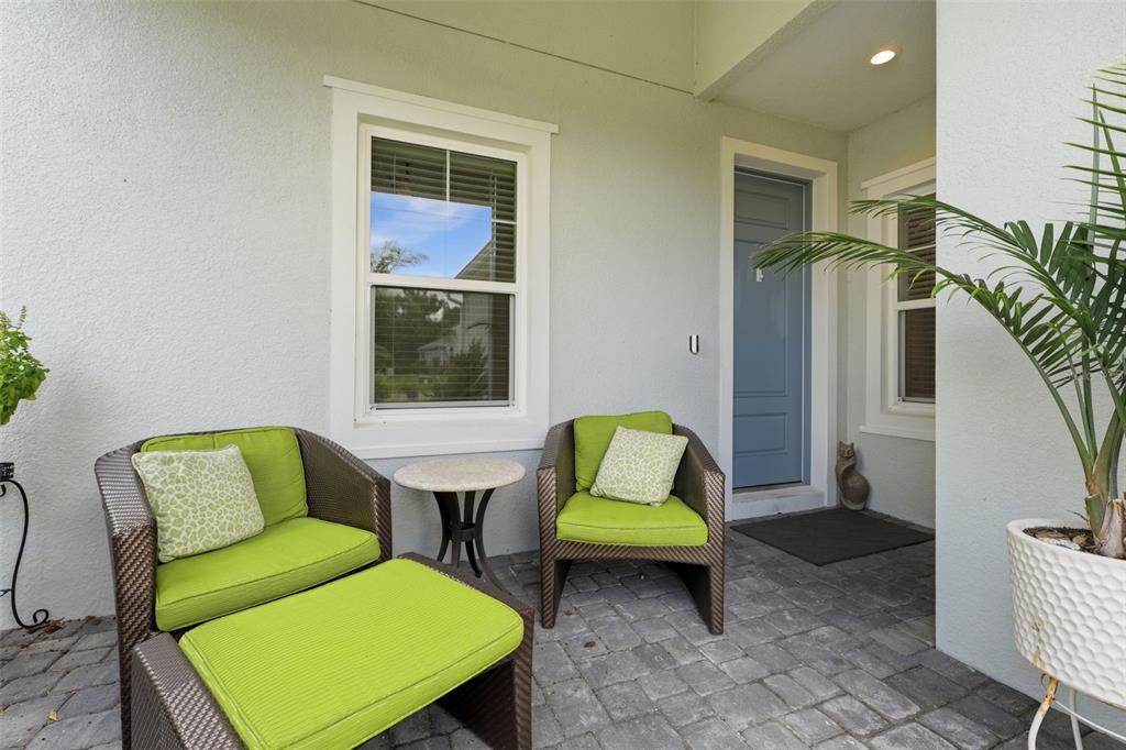A paved patio features two wicker chairs with lime green cushions and a small table — 12468 PALATKA DRIVE, VENICE, FL