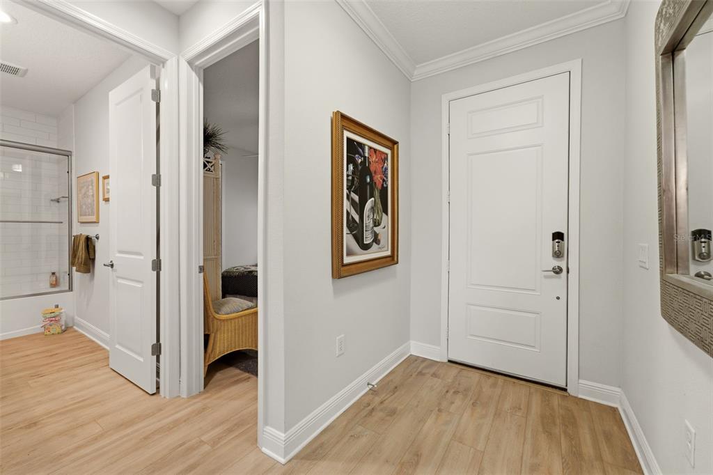 An entryway features light wood-look flooring, a white door, and a framed painting on the wall — 12468 PALATKA DRIVE, VENICE, FL