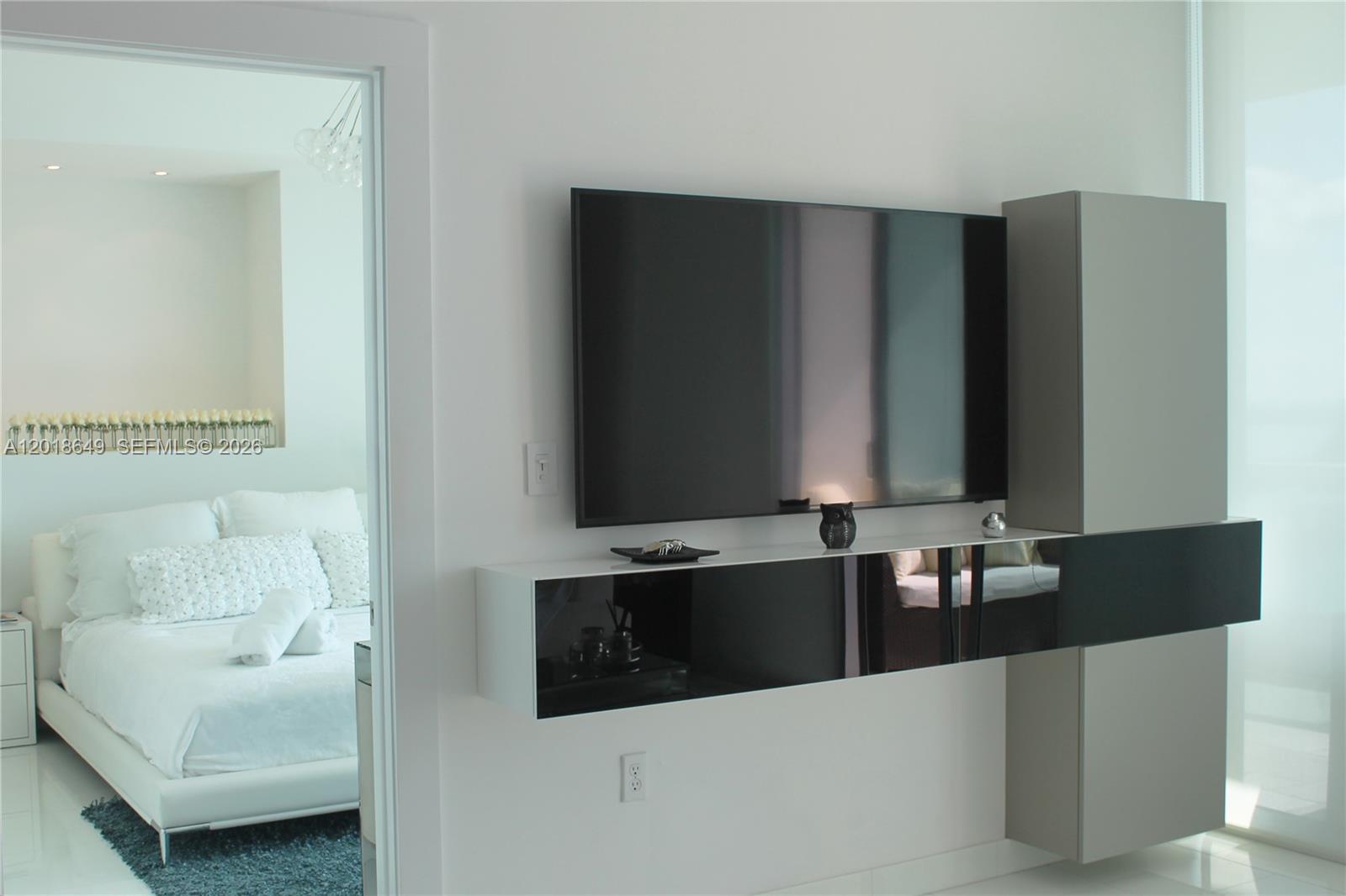 A wall-mounted television sits above a modern, floating black and white media console — 900 Biscayne Blvd # 3207, Miami FL 33132, MIAMI, FL
