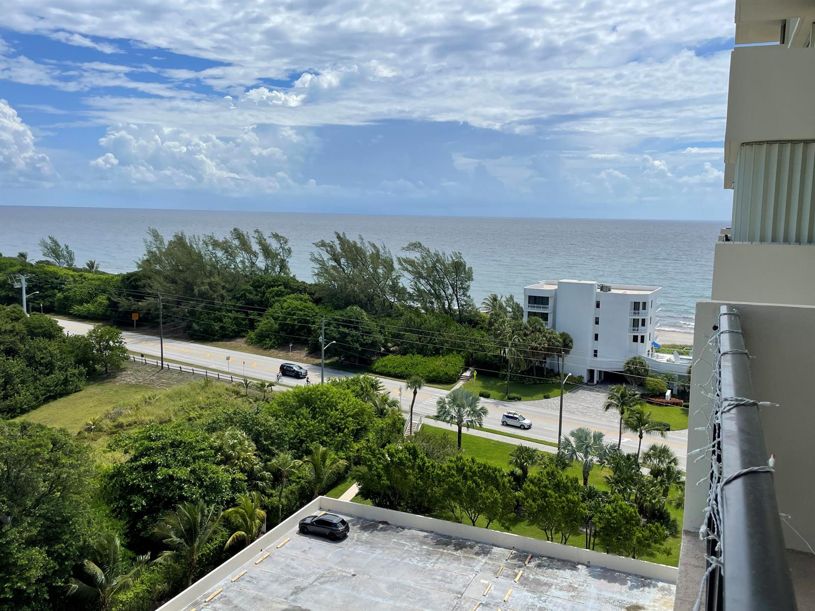 An elevated view of a coastal road, lush greenery, a white building, and the ocean — 2121 N Ocean Boulevard # 1204e, Boca Raton FL 33431, BOCA RATON, FL