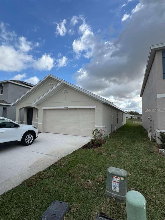 A beige single-story house with a two-car garage and a white car parked outside — 37066 KINGS CROWN DRIVE, ZEPHYRHILLS, FL