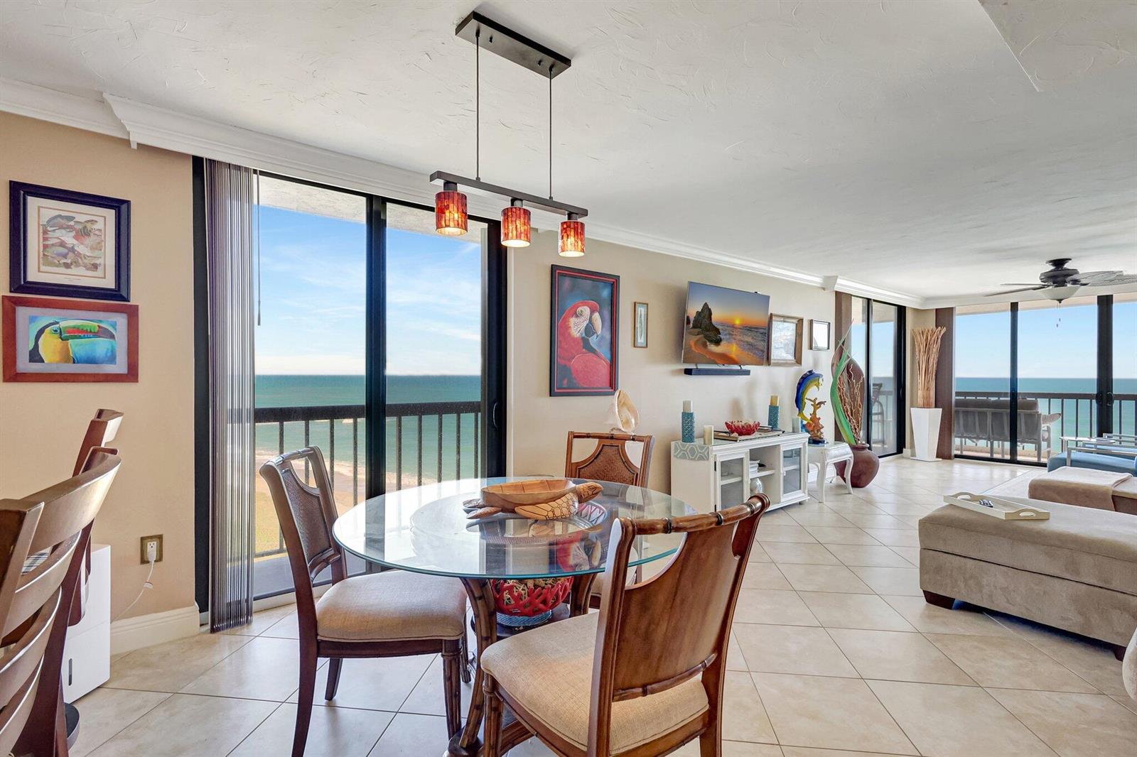 A dining area with a glass table and ocean views through large sliding glass doors — 10680 S Ocean Drive # 901, Jensen Beach FL 34957, JENSEN BEACH, FL