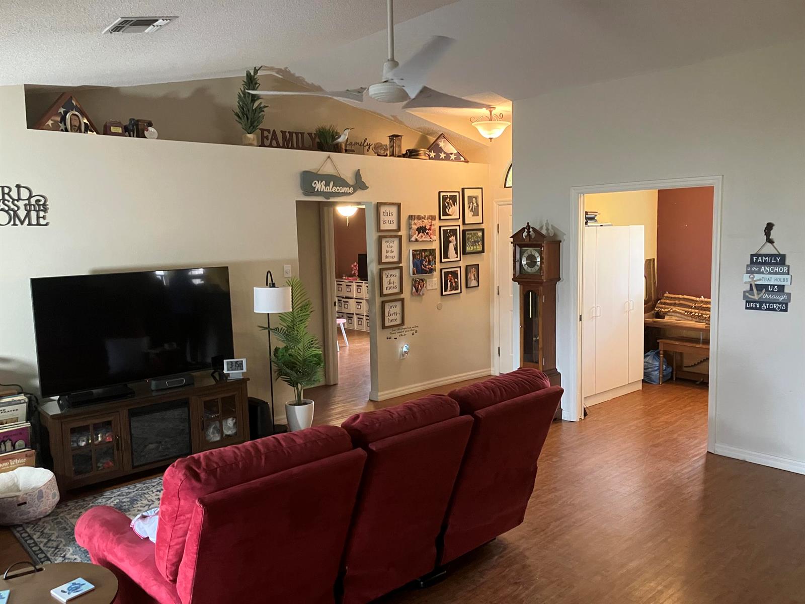 A living room features a red sofa, a television console, and a grandfather clock — 14050 Brighton Street, Spring Hill FL 34609, SPRING HILL, FL