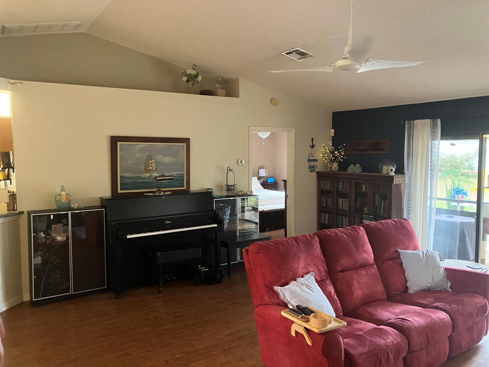 A living room features a black piano, a red sofa, and a doorway to a bedroom — 14050 Brighton Street, Spring Hill FL 34609, SPRING HILL, FL