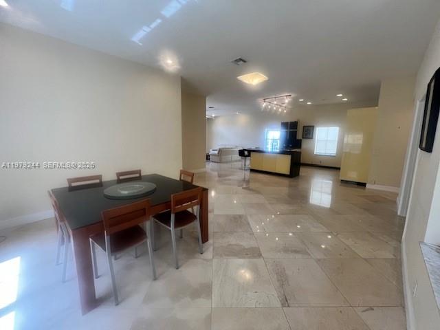 A kitchen island with a dark countertop and faucet overlooks a dining area — 803 Vista Meadows Dr, Weston FL 33327, WESTON, FL