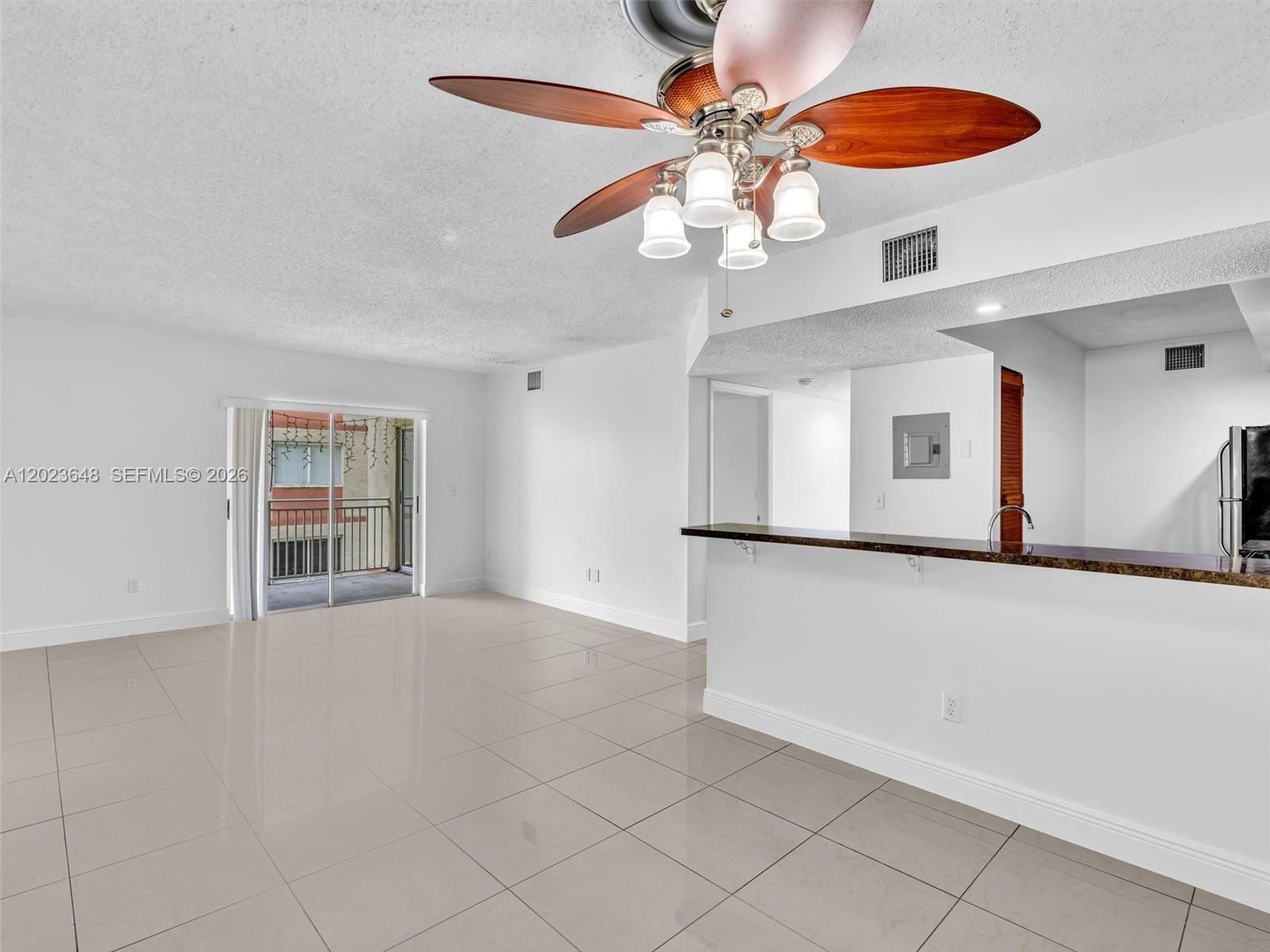 This living room features white walls, light tile flooring, a ceiling fan, and a balcony — 18850 NW 57th Ave # 208, Hialeah FL 33015, HIALEAH, FL