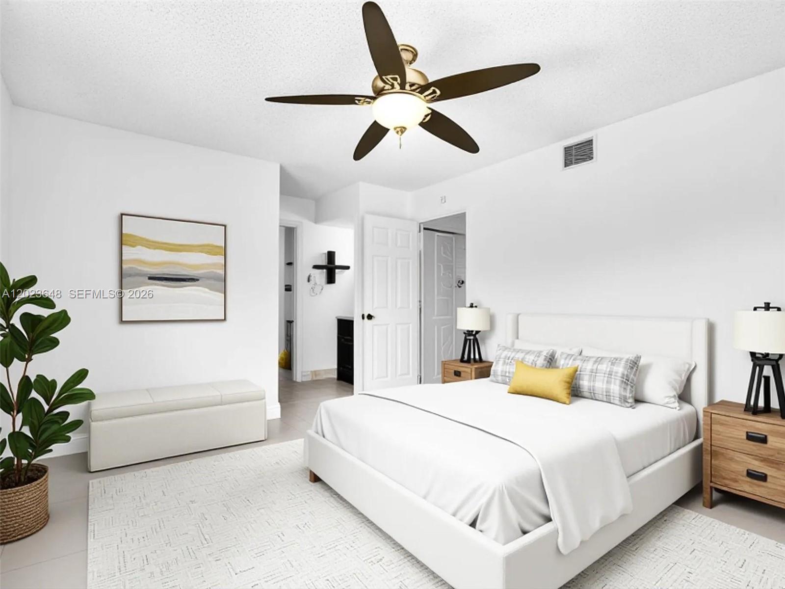 A bedroom features a white bed, a ceiling fan, and a bench on a rug — 18850 NW 57th Ave # 208, Hialeah FL 33015, HIALEAH, FL