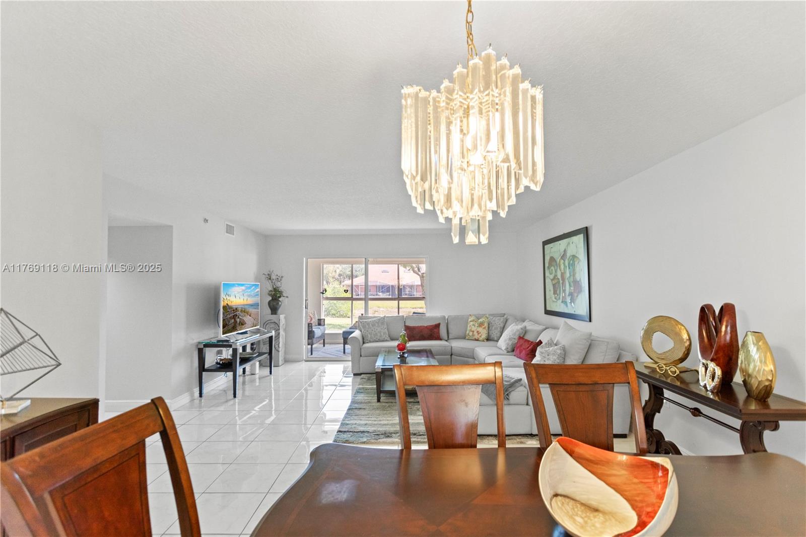 A living and dining area features white tile floors, a crystal chandelier, and a sectional sofa — 5876 Regal Glen Dr # 101, Boynton Beach FL 33437, BOYNTON BEACH, FL