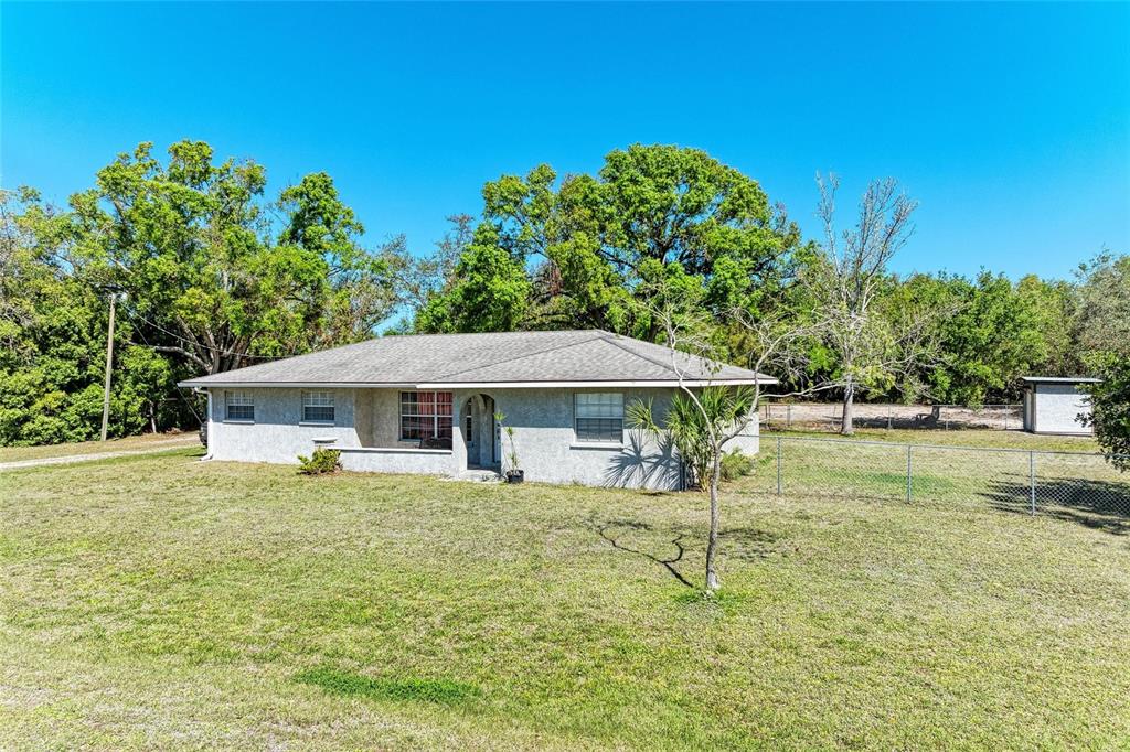 A single-story house with a light-colored stucco exterior sits on a large, grassy lot — 4007 45TH STREET E, BRADENTON, FL