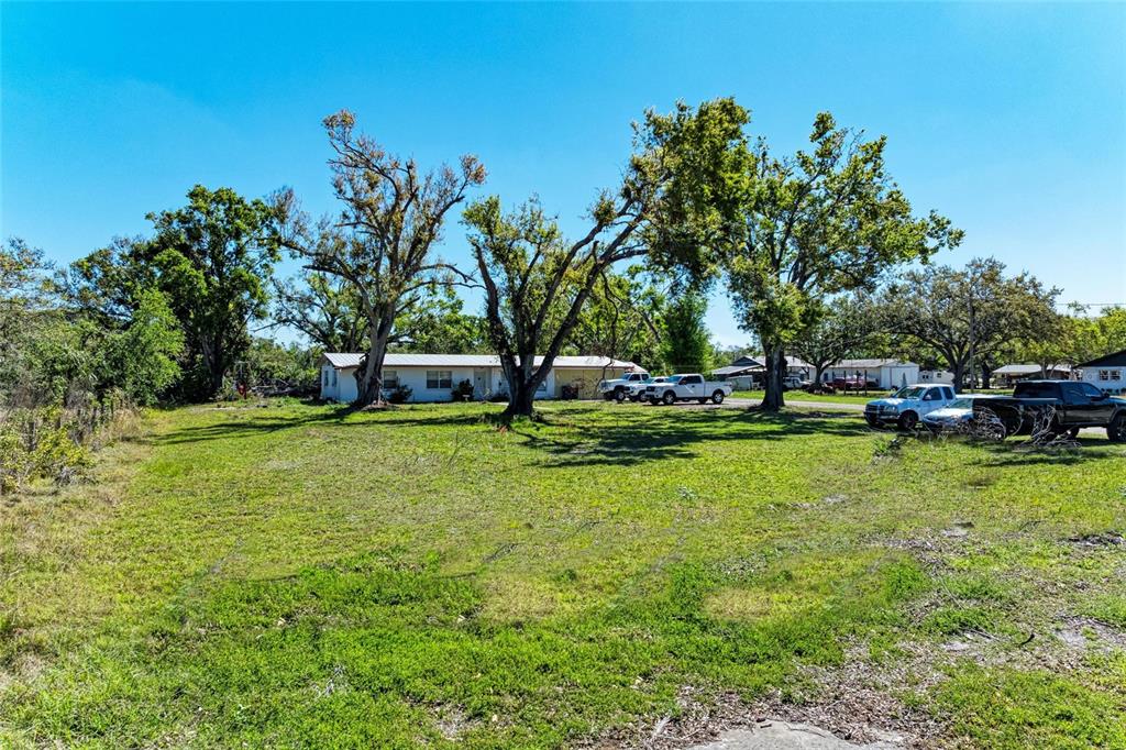 A single-story house sits behind a large grassy yard with several mature trees — 4007 45TH STREET E, BRADENTON, FL