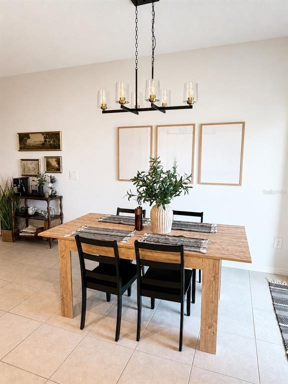 A dining room features a wooden table, black chairs, a linear chandelier, and wall art — 21161 THREADFIN WAY, LAND O LAKES, FL