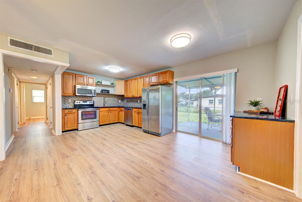 A kitchen with wood cabinets, stainless steel appliances, and wood-look flooring leads to a patio — 813 7TH STREET, MERRITT ISLAND, FL