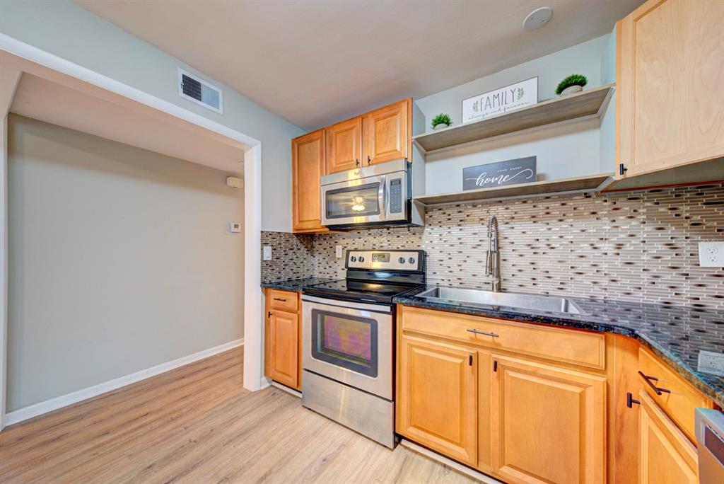 A kitchen features light wood cabinets, stainless steel appliances, a tiled backsplash, and granite countertops — 813 7TH STREET, MERRITT ISLAND, FL