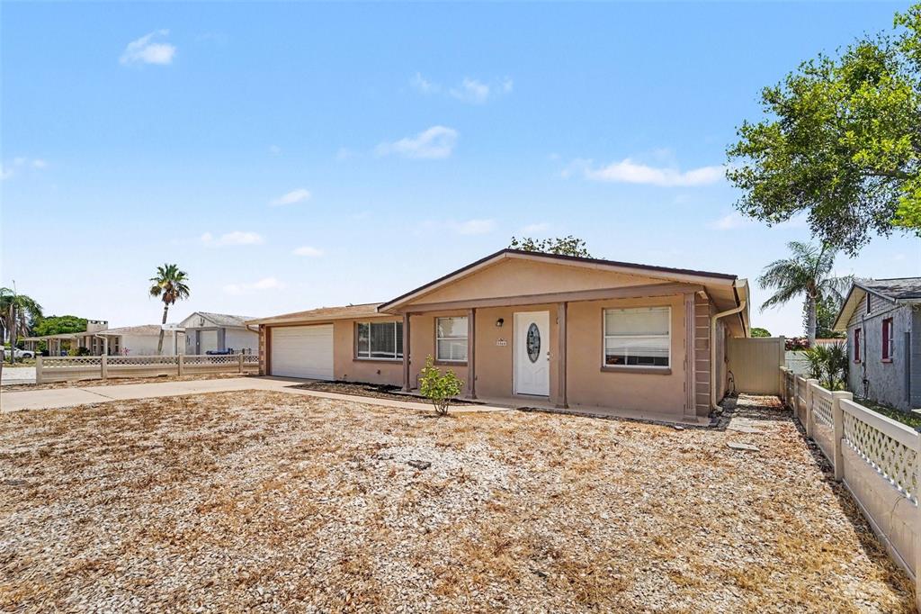 A single-story house with a beige exterior, a garage, and a gravel front yard — 3344 TRASK DRIVE, HOLIDAY, FL