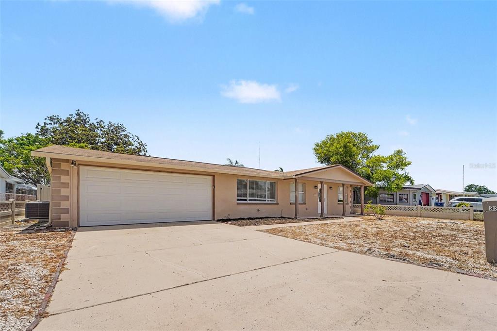 A single-story house with a beige exterior, a two-car garage, and a concrete driveway — 3344 TRASK DRIVE, HOLIDAY, FL