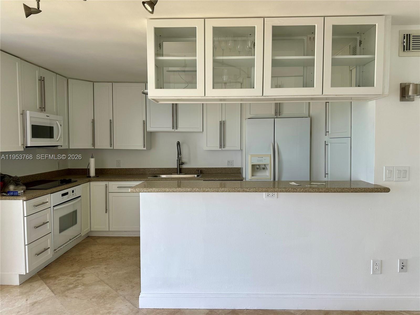 A kitchen features white cabinets, a granite countertop, and a peninsula overlooking the room — 881 Ocean Dr # 10D, Key Biscayne FL 33149, KEY BISCAYNE, FL