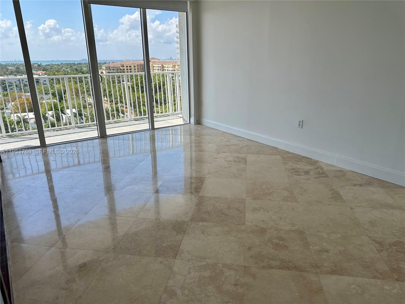 An empty room features polished stone tile flooring and a sliding glass door to a balcony — 881 Ocean Dr # 10D, Key Biscayne FL 33149, KEY BISCAYNE, FL