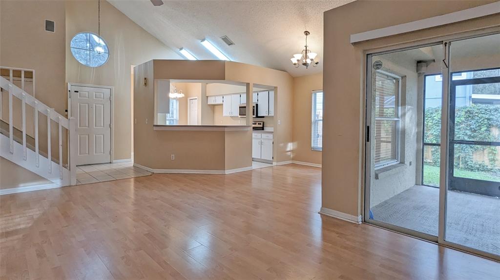 An open-concept living area with light wood flooring, a kitchen pass-through, and a screened porch — 4029 QUAIL BRIAR DRIVE, VALRICO, FL