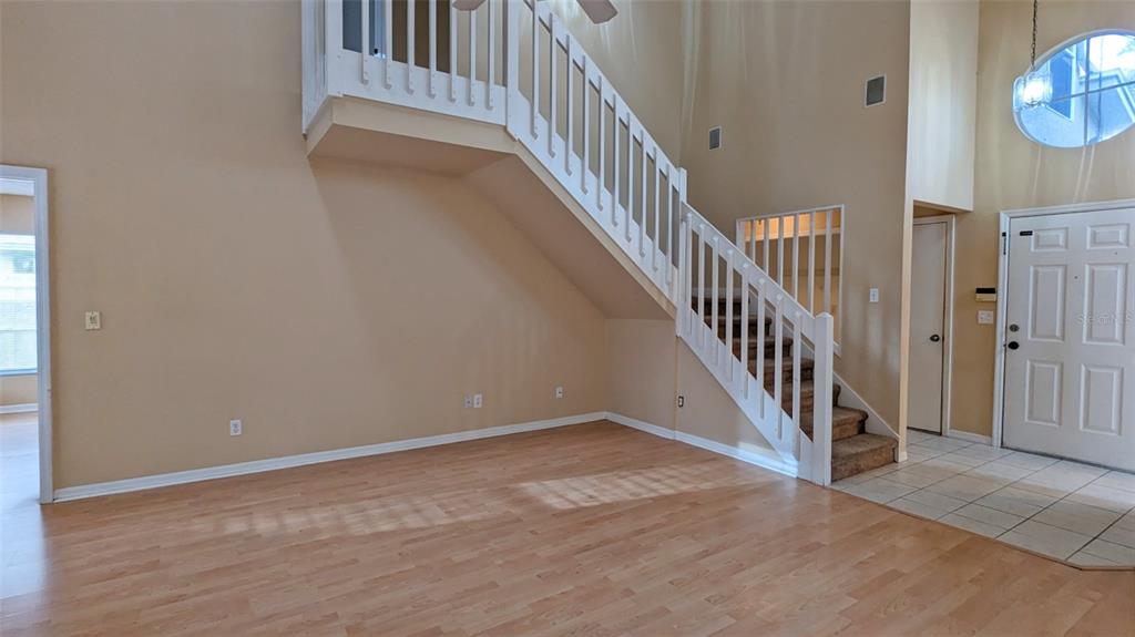 An interior view of a living room featuring a staircase with white railings and wood flooring — 4029 QUAIL BRIAR DRIVE, VALRICO, FL