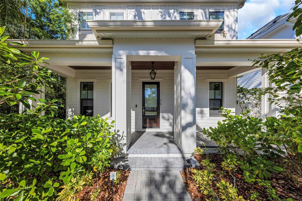 A white two-story house features a covered front porch with a dark wood door — 319 12TH AVENUE NE, ST PETERSBURG, FL