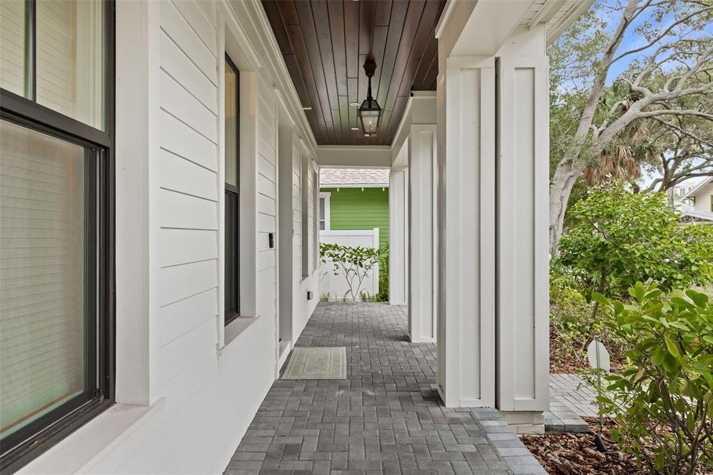 A covered porch features white siding, a dark wood ceiling, and gray paver flooring — 319 12TH AVENUE NE, ST PETERSBURG, FL