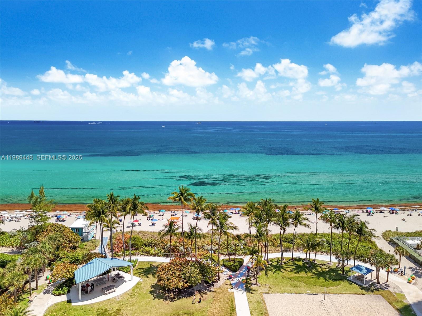 An open-concept living and dining area features light wood flooring, a modern kitchen, and windows — 1865 S Ocean Dr # 21C, Hallandale Beach FL 33009, HALLANDALE BEACH, FL