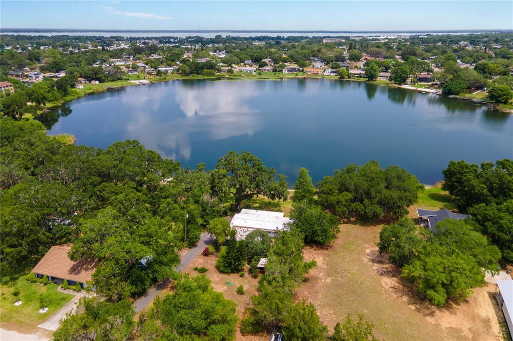 An aerial view shows a house with a white roof situated near a large lake — 1451 OSCEOLA AVENUE, TAVARES, FL