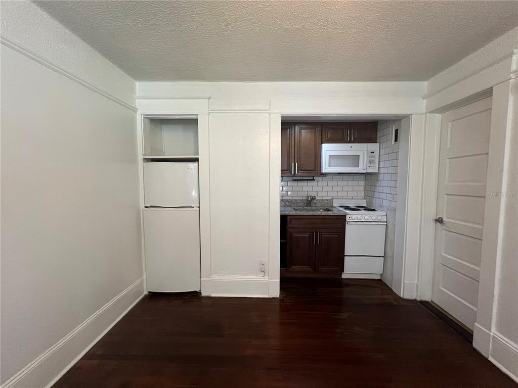 A small kitchen area features dark wood cabinets, white appliances, and a built-in refrigerator — 510 E JACKSON ST UNIT 2, ORLANDO, FL