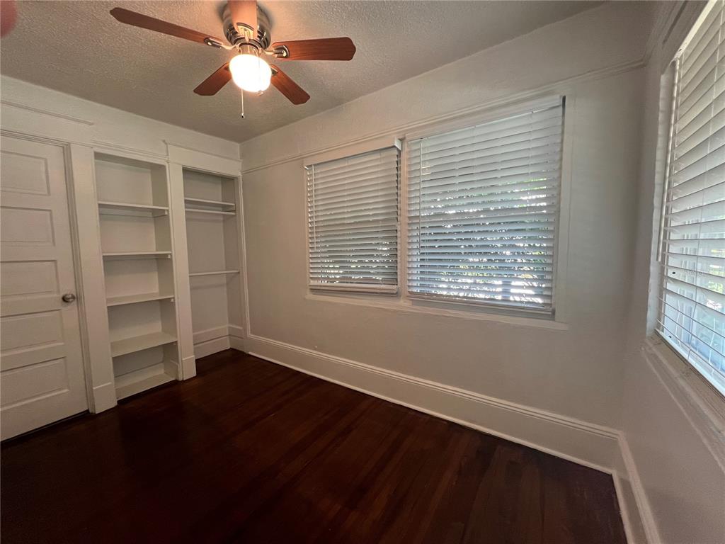 An empty bedroom features dark hardwood floors, white built-in shelving, and windows with white blinds — 510 E JACKSON ST UNIT 2, ORLANDO, FL