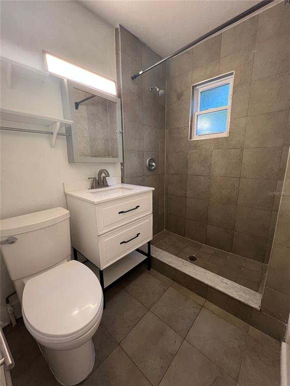 A bathroom features a white vanity, a toilet, and a walk-in shower with tiled walls — 510 E JACKSON ST UNIT 2, ORLANDO, FL