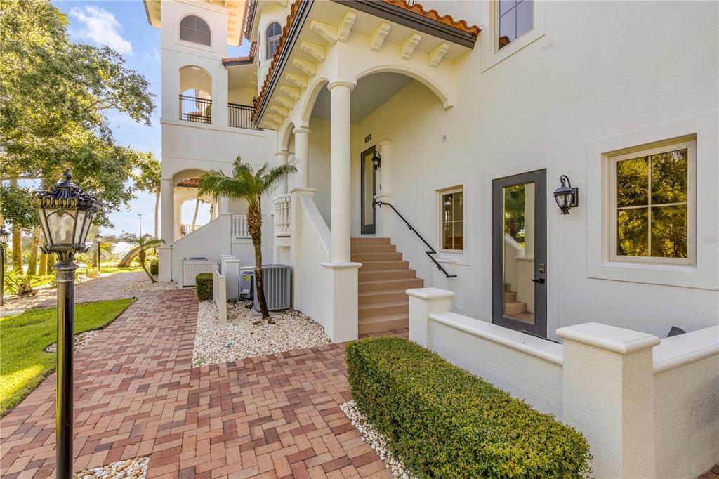 A paved walkway leads to a covered staircase and entrance of a white stucco building — 5090 RIVERSIDE DRIVE UNIT 105, PORT ORANGE, FL