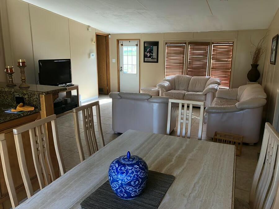 A dining area with a stone table leads into a living room with beige furniture — 6741 NW 193rd Street, FL 32686, FL