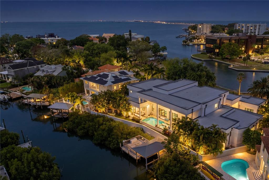 An aerial night view of a waterfront luxury home with pools, docks, and solar panels — 2 SANDPIPER ROAD, TAMPA, FL