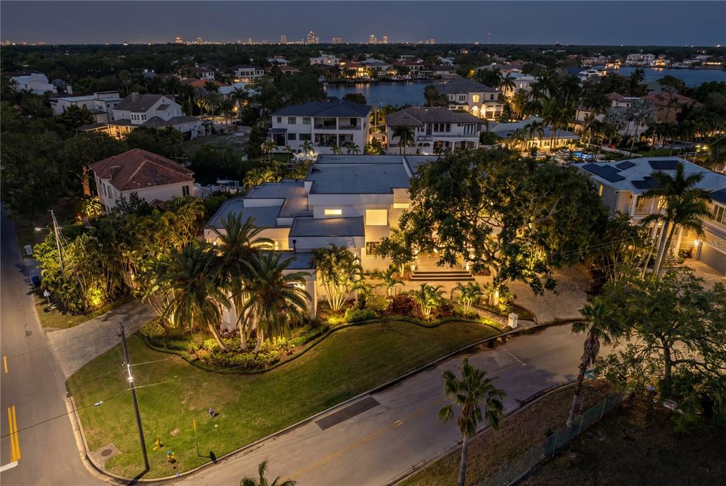 An aerial view shows a modern white house at night surrounded by trees and landscaping — 2 SANDPIPER ROAD, TAMPA, FL