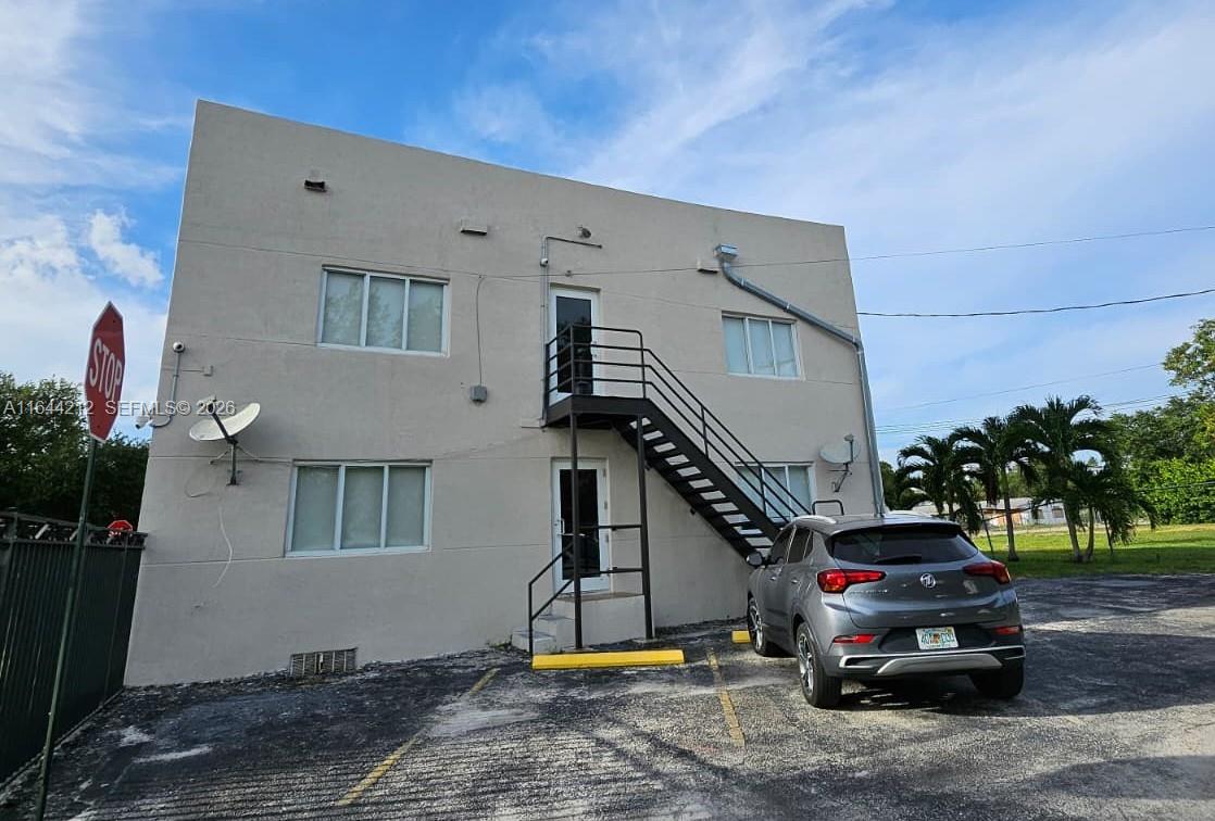 A two-story beige building features an exterior metal staircase and a parked gray SUV — 2500 NE 192nd St, Miami FL 33180, MIAMI, FL