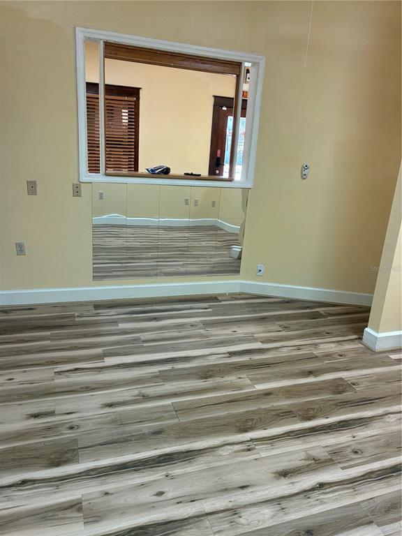 A room with wood-look flooring, a large interior window, and mirrored wall panels below — 814 N MAIN STREET, KISSIMMEE, FL