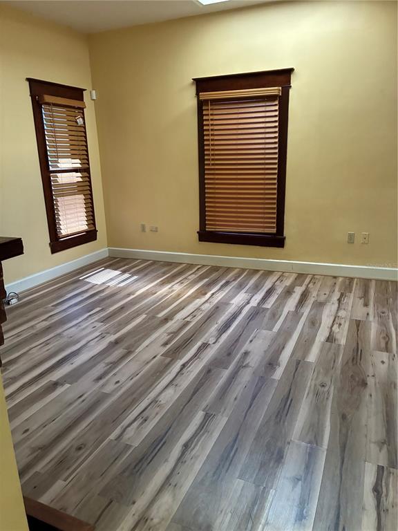 An empty room features yellow walls, dark wood window trim, and light-toned wood-look flooring — 814 N MAIN STREET, KISSIMMEE, FL